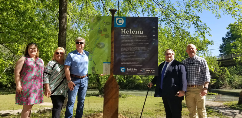 People standing by upright sign Cahaba Blueway Helena